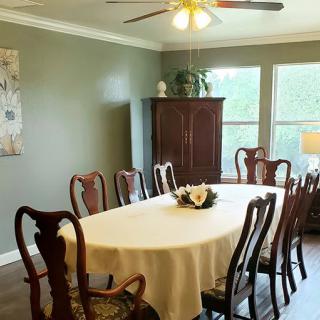 A formal dining room with a table set for gathering, featuring classic wooden chairs and a white tablecloth.