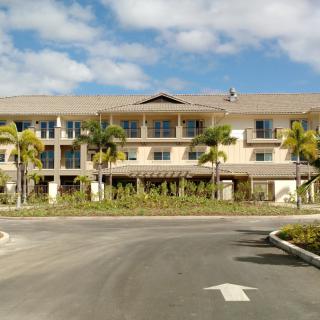 A modern building surrounded by palm trees under a partly cloudy sky.
