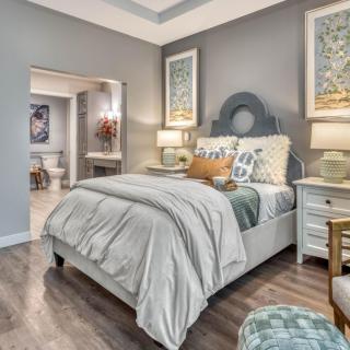 A modern and cozy bedroom with elegant decor, featuring a neatly made bed, matching nightstands, and stylish artwork.