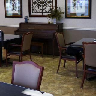 A cozy dining area featuring a piano, tables and chairs with wall art decorations.