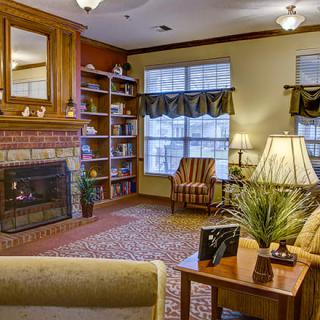A cozy living room with a fireplace, armchair, and bookshelf.
