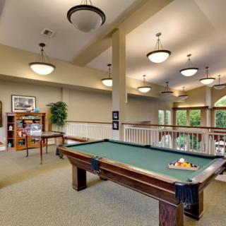 A well-lit recreation room featuring a pool table and large windows.