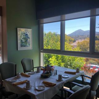 A cozy dining area with a beautifully set table and a scenic view of the mountains through large windows.