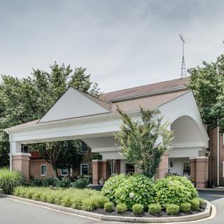 A view of a hotel entrance surrounded by lush greenery.