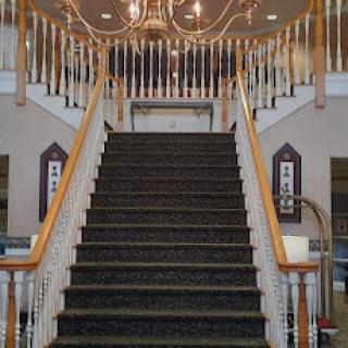 A grand staircase featuring a beautiful chandelier, inviting guests into an elegant space.