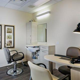 A modern office space featuring a desk, chairs, and a sink for convenient functionality.
