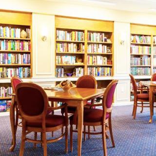 A quiet library reading area with bookshelves and wooden tables.