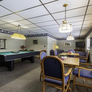 A recreational game room featuring a pool table and a seating area with chairs under decorative lighting.