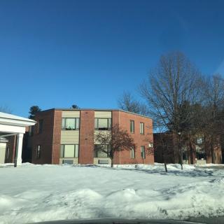 A brick residential building surrounded by snow under a clear blue sky.