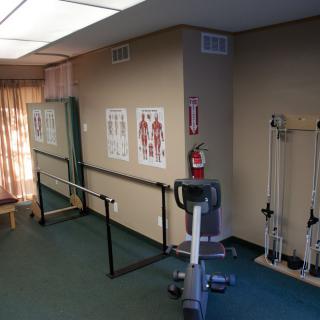 A physical therapy room equipped with exercise machines and anatomical charts on the walls.