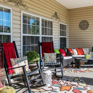 A cozy porch with rocking chairs, colorful cushions, and decorative elements.
