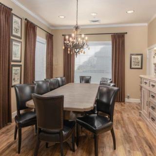 A stylish dining room with a long table, elegant chandelier, and wooden flooring.