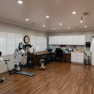 A spacious office area with exercise equipment and desks, featuring a wooden floor and white cabinetry.