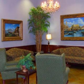 A cozy lobby with armchairs, a sofa, and elegant decor including paintings and a chandelier.
