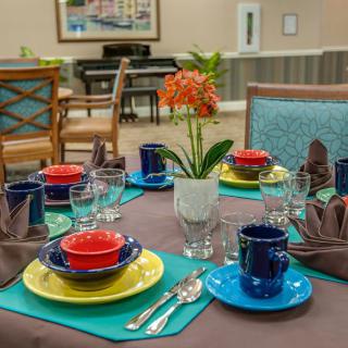 A dining table beautifully set with colorful dishes and a floral centerpiece.