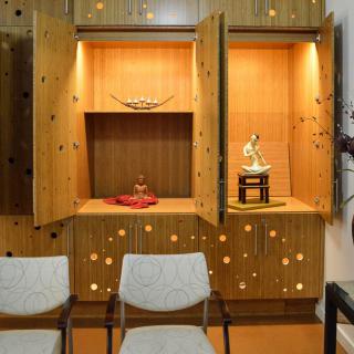 A serene indoor altar with a Buddha statue, wooden cabinets, and seating.