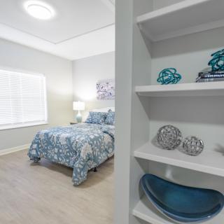 A modern bedroom with a blue and white color scheme, featuring neatly arranged shelves and stylish decor.