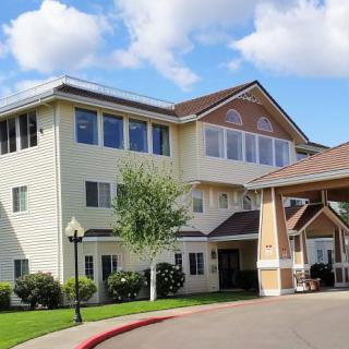 A three-story residential building with a covered entrance under a partly cloudy sky.