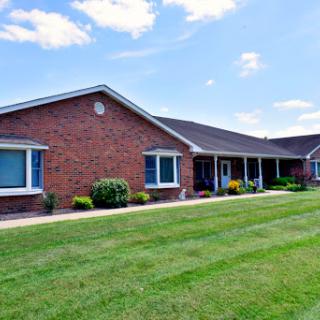 A charming single-story brick house with blue shutters and a well-maintained lawn.
