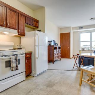 A cozy apartment kitchen and dining area with wooden cabinets and a white refrigerator.