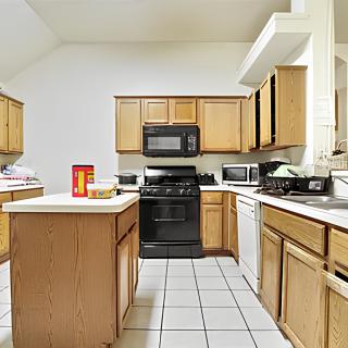 A modern kitchen with wooden cabinets, featuring an island and various appliances.
