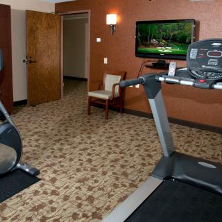 A small fitness room featuring a treadmill and television.