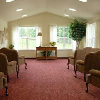 A bright waiting room with chairs arranged around a carpeted area and large windows letting in natural light.