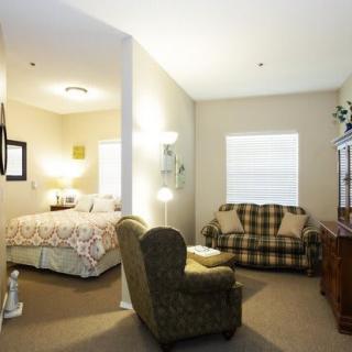 A cozy room featuring a bed and a small living area with an armchair and sofa.