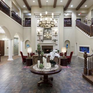 Spacious luxury living room with high ceilings, elegant furniture, and a grand chandelier.