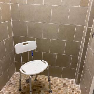 A bathroom with a shower chair for accessibility.