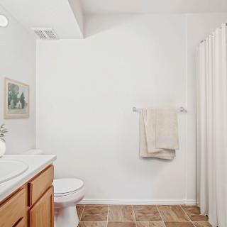 A bright and simple bathroom featuring a vanity, shower curtain, and wooden accents.