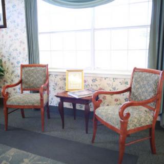 A cozy living room corner with two upholstered chairs and a small table by the window.
