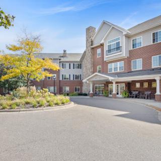 A welcoming hotel entrance surrounded by greenery under a clear blue sky.