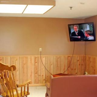 A cozy living room with wood paneling, a rocking chair, and a mounted television.