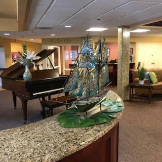 A well-decorated lobby featuring a grand piano and a ship model on a granite counter.
