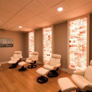 A serene spa room featuring cozy lounge chairs and illuminated salt walls, designed for relaxation and wellness.