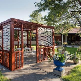 A charming wooden gazebo set in a serene garden, perfect for relaxation and outdoor gatherings.