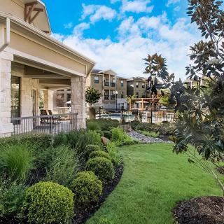 A beautiful home with a well-manicured garden and a spacious porch overlooking the greenery.