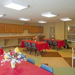 A well-lit classroom with tables covered in red tablecloths and decorated with flowers.
