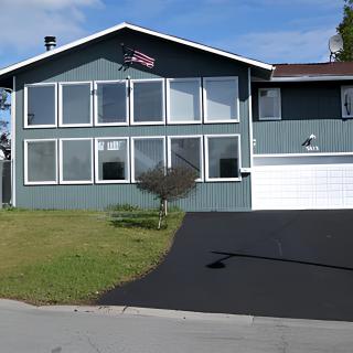 A residential house with large front windows, a garage, and a driveway.