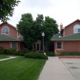 A residential house with a green lawn and trees.