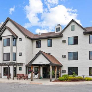 A three-story hotel building with a sloped roof under a partly cloudy sky.