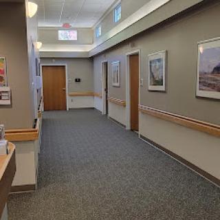 A well-lit hospital hallway featuring artwork and wooden doors.