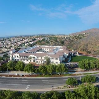 Aerial view of a large building surrounded by roads and residential areas with hills in the background.