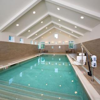 A modern indoor swimming pool with vaulted ceilings and tiled walls, offering a serene environment for relaxation.