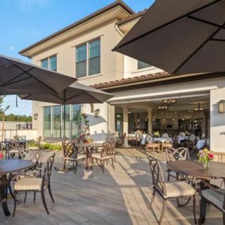 An inviting outdoor patio with tables, chairs, and large umbrellas, set against a modern building exterior.