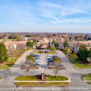 Aerial view of a large building with a parking lot surrounded by trees.