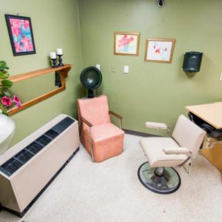 A cozy salon room with a hair dryer, chairs, and wall decorations.