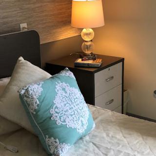A cozy bedroom setup featuring a stylish lamp, decorative pillow, and modern nightstand.