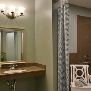 A modern bathroom with a wall-mounted sink, mirror, and decorative lighting fixture.